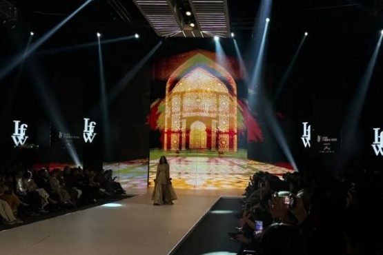 LAAM Fashion Week Season 2 Day 2 runway show in Lahore featuring a model in traditional attire against an illuminated architectural backdrop celebrating Pakistani fashion and heritage.